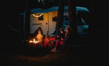 Family enjoying a warm night by the campfire beside their campervan in Lithuania.