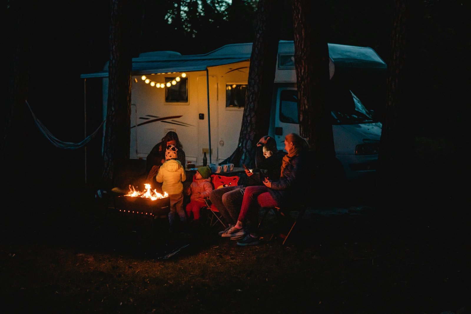 Family enjoying a warm night by the campfire beside their campervan in Lithuania.